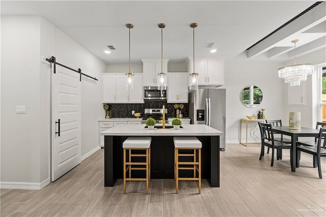 5516 N Crown Pt, Pharr, TX 78577 - kitchen featuring stainless steel appliances, a barn door, a sink, backsplash, and white cabinets
