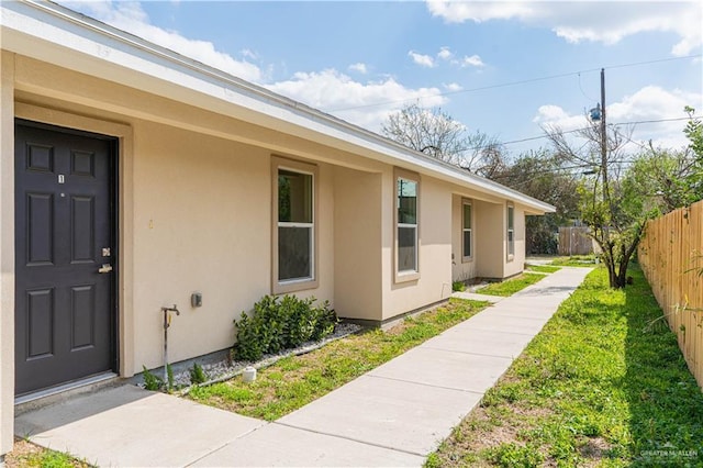 view of property exterior with a yard, fence, and stucco siding