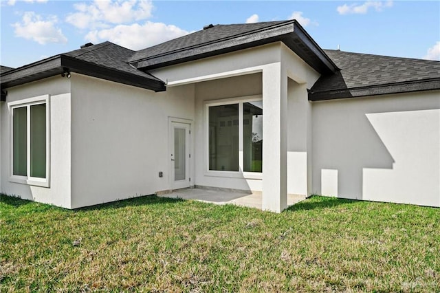 rear view of property with a patio area, a yard, and stucco siding