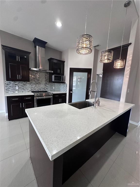 5013 Nevis Dr, Edinburg, TX 78539 - kitchen featuring wall chimney range hood, appliances with stainless steel finishes, a sink, backsplash, and light tile patterned floors