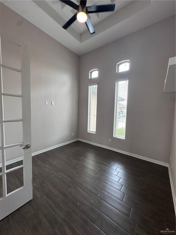 5013 Nevis Dr, Edinburg, TX 78539 - spare room featuring dark wood-style floors, a ceiling fan, baseboards, and a tray ceiling
