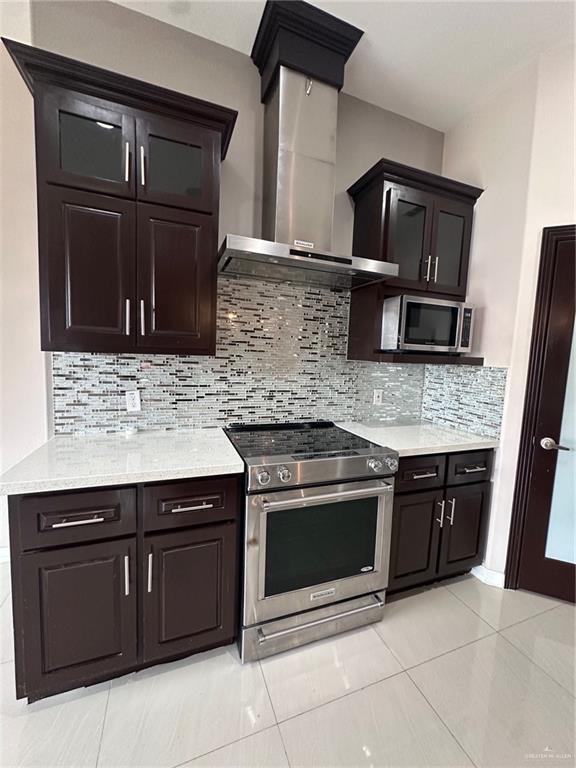 5013 Nevis Dr, Edinburg, TX 78539 - kitchen with stainless steel appliances, wall chimney range hood, light countertops, and light tile patterned floors