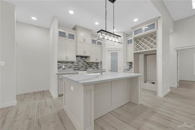 1007 Broken Arrow Dr, Alamo, TX 78516 - kitchen featuring a kitchen island with sink, a sink, light wood-style flooring, and tasteful backsplash