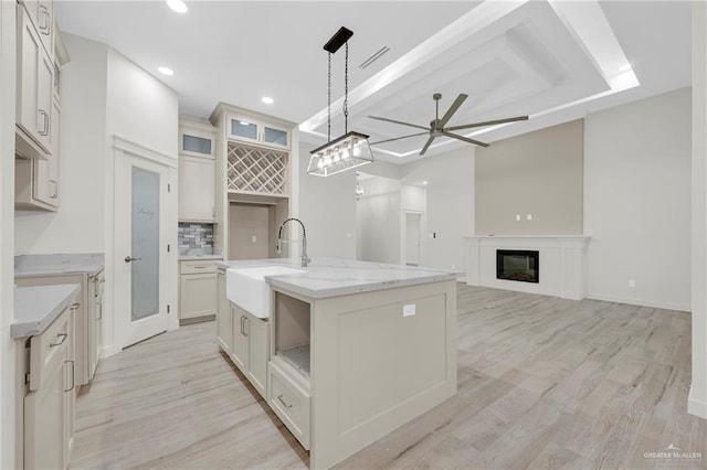 1007 Broken Arrow Dr, Alamo, TX 78516 - kitchen with an island with sink, decorative backsplash, decorative light fixtures, a sink, and a ceiling fan