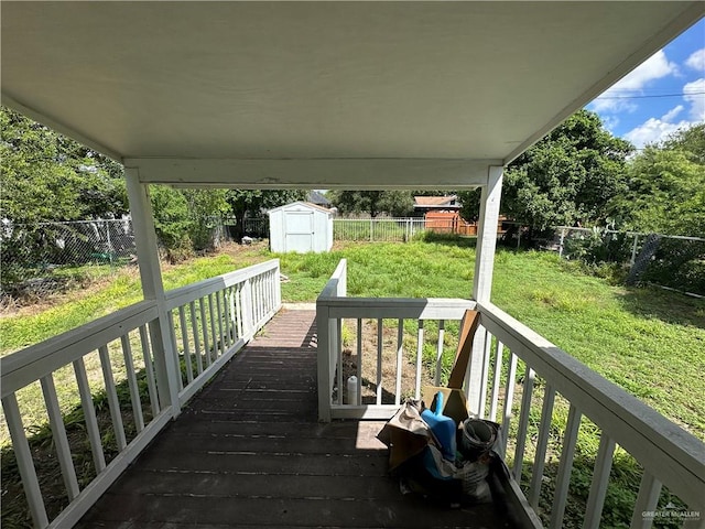 wooden terrace with a lawn and a storage unit