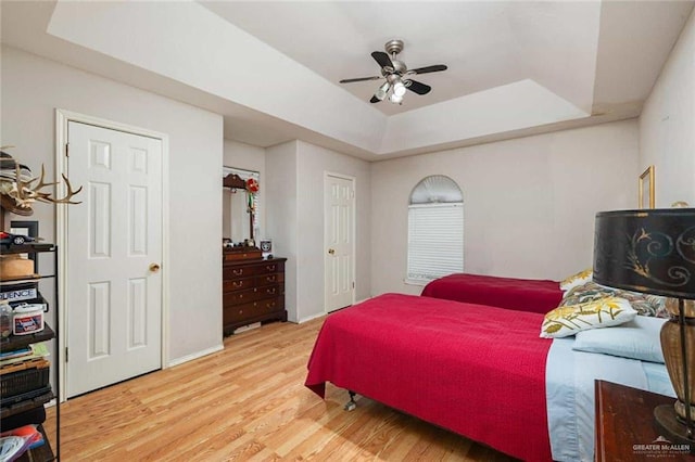 bedroom featuring a raised ceiling, ceiling fan, and hardwood / wood-style flooring