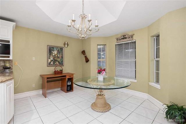 tiled dining space with a chandelier and a raised ceiling