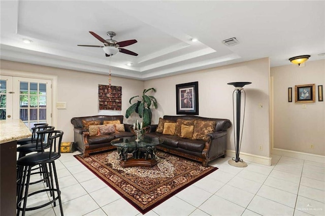 living room with ceiling fan, french doors, light tile patterned floors, and a tray ceiling