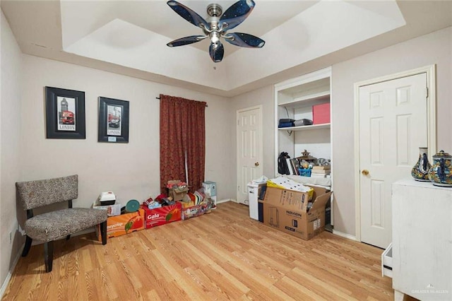 recreation room featuring hardwood / wood-style flooring, ceiling fan, and a tray ceiling