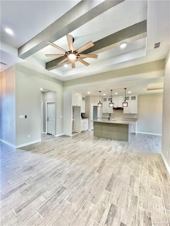 unfurnished living room with sink, a raised ceiling, and ceiling fan