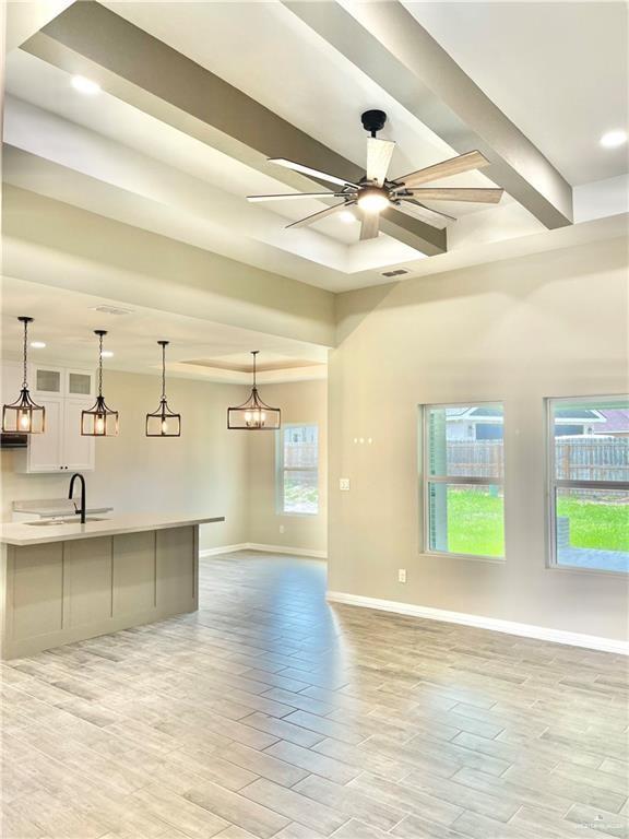 interior space with sink, ceiling fan with notable chandelier, beamed ceiling, and light wood-type flooring