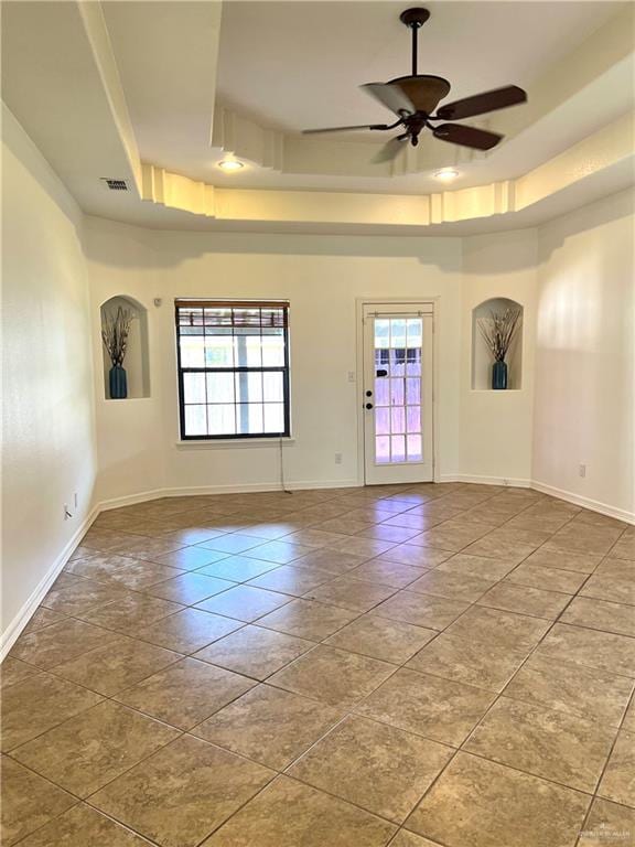 tiled spare room with ceiling fan and a tray ceiling