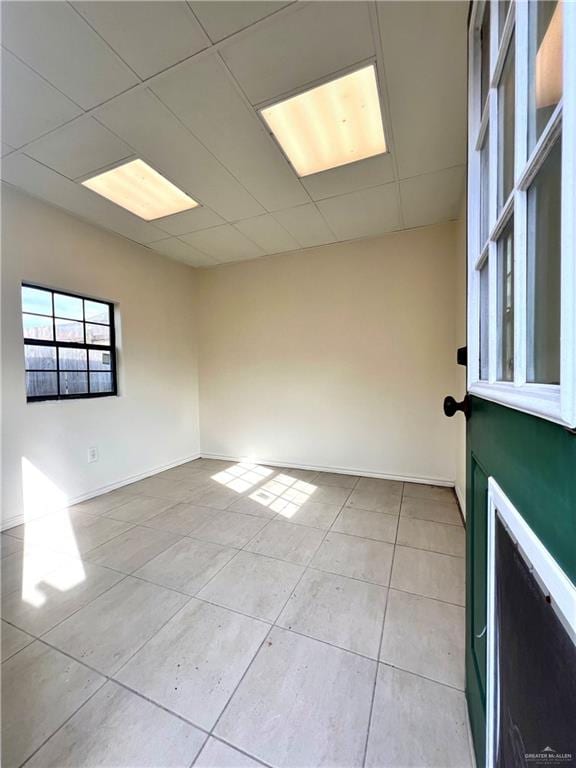 tiled spare room featuring a drop ceiling