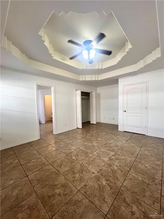 unfurnished bedroom with a raised ceiling, ceiling fan, and dark tile patterned floors