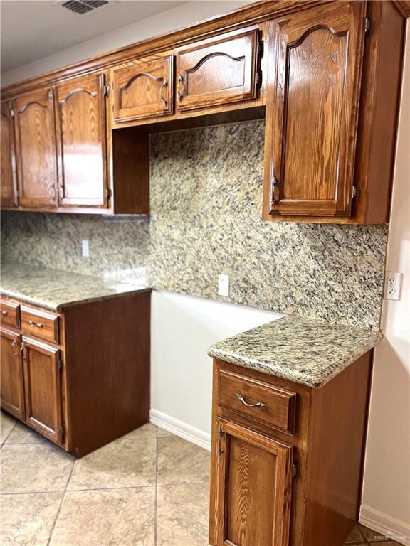 kitchen with light tile patterned floors, tasteful backsplash, and light stone counters