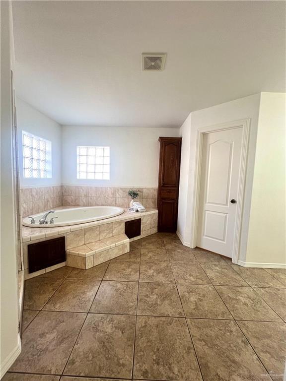 bathroom featuring tile patterned flooring and tiled bath