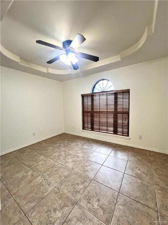 unfurnished room featuring a raised ceiling, ceiling fan, and tile patterned flooring