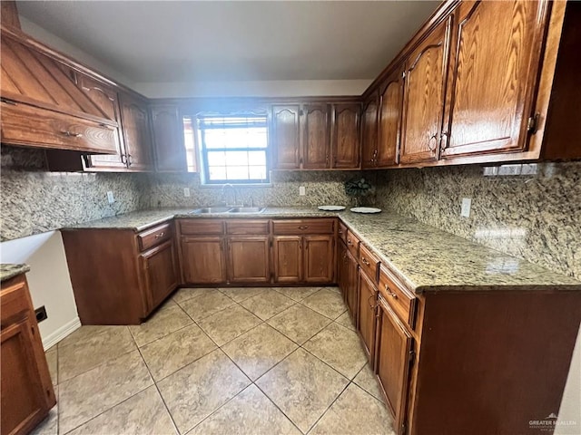 kitchen with backsplash, light stone countertops, sink, and light tile patterned flooring