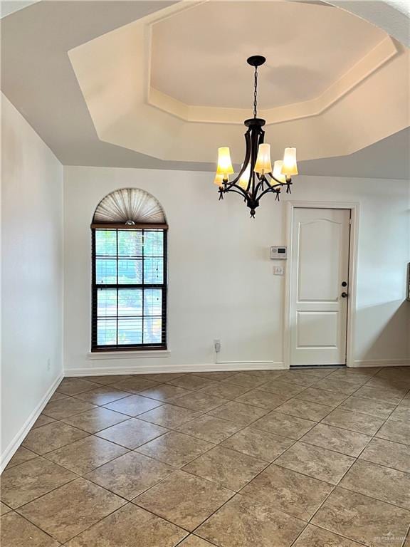 unfurnished room with a tray ceiling and an inviting chandelier