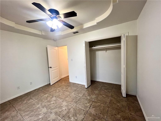 unfurnished bedroom with ceiling fan, a raised ceiling, and a closet