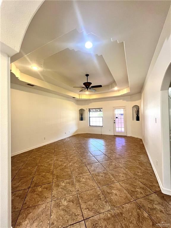 unfurnished room with a raised ceiling and ceiling fan