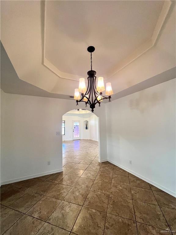 unfurnished dining area with a notable chandelier and a tray ceiling