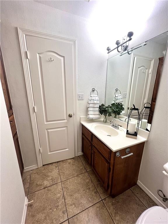 bathroom with tile patterned flooring, vanity, a notable chandelier, and toilet