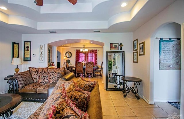 2209 Benito A Ramirez Rd, Edinburg, TX 78542 - living area featuring a tray ceiling, light tile patterned flooring, arched walkways, a chandelier, and a ceiling fan