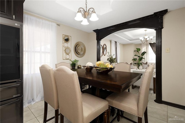 tiled dining area with a notable chandelier and a raised ceiling