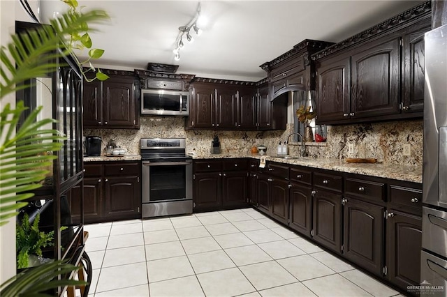 kitchen featuring tasteful backsplash, dark brown cabinets, stainless steel appliances, sink, and light tile patterned flooring