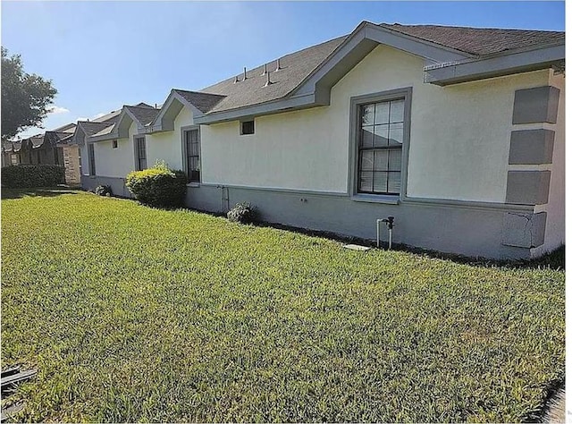 view of side of property with stucco siding and a yard