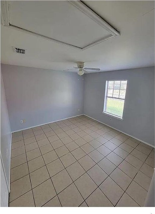 empty room featuring a ceiling fan, visible vents, and light tile patterned flooring