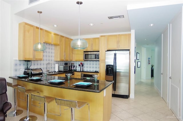 kitchen featuring a sink, stainless steel appliances, light brown cabinetry, visible vents, and a peninsula
