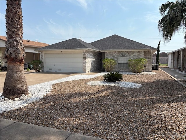 view of front of property with central air condition unit, a garage, concrete driveway, brick siding, and roof with shingles