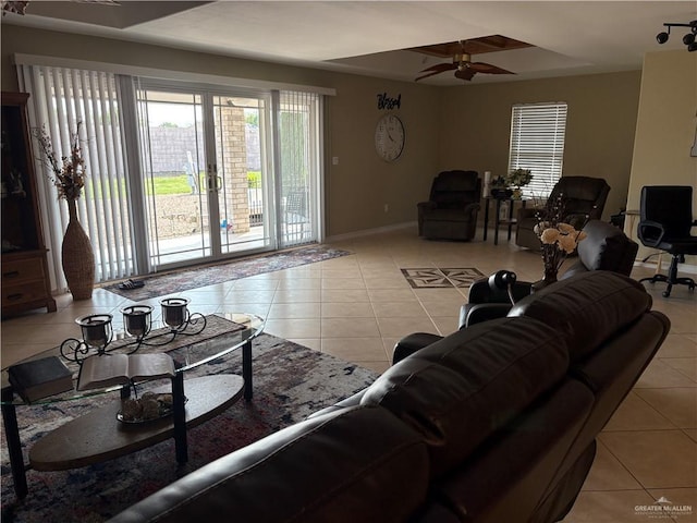 living room with baseboards, ceiling fan, a raised ceiling, and light tile patterned floors