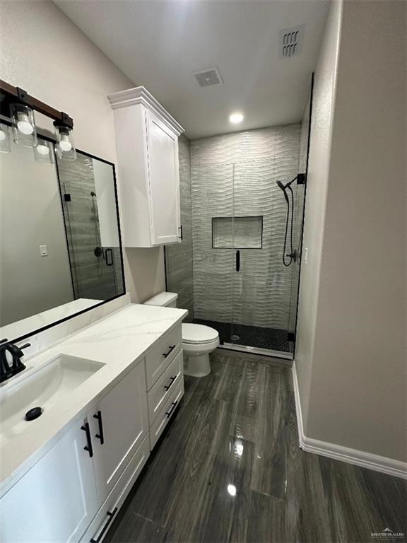 bathroom featuring toilet, vanity, wood-type flooring, and walk in shower