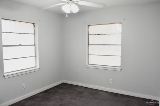 spare room with ceiling fan and dark carpet