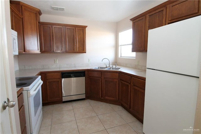 kitchen featuring tile countertops, sink, light tile patterned flooring, and white appliances