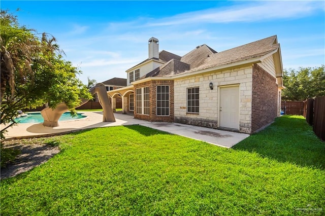 back of property featuring a fenced in pool, a fenced backyard, a yard, a patio area, and stone siding