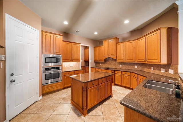 kitchen with stainless steel appliances, a center island, a sink, visible vents, and backsplash