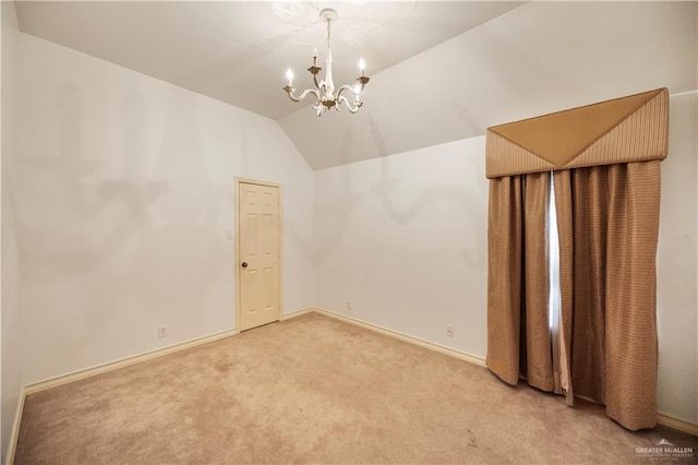 unfurnished room with light carpet, vaulted ceiling, baseboards, and an inviting chandelier