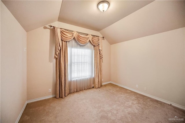 empty room featuring vaulted ceiling, baseboards, and carpet floors