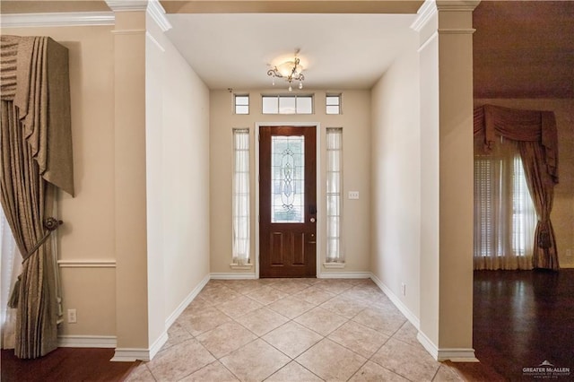 foyer featuring light tile patterned floors, baseboards, and decorative columns