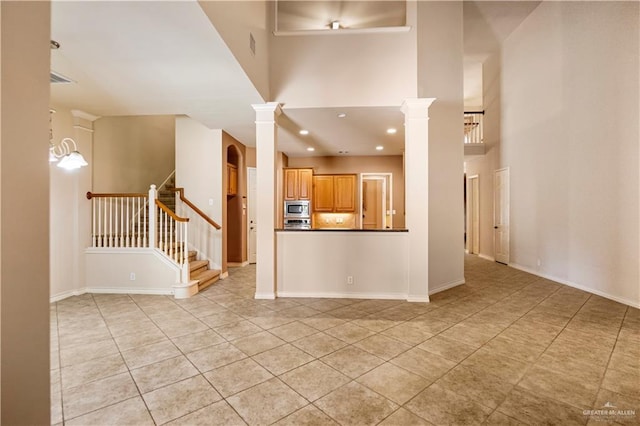 unfurnished living room with stairs, light tile patterned floors, decorative columns, a towering ceiling, and recessed lighting