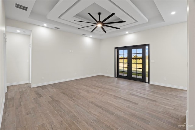 spare room featuring a tray ceiling, french doors, ceiling fan, and light wood-type flooring