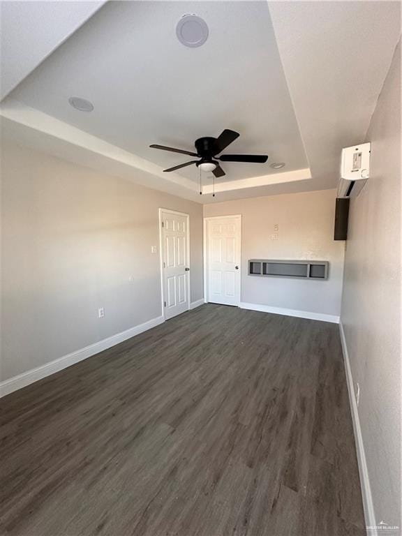 unfurnished living room with dark hardwood / wood-style floors, a raised ceiling, and ceiling fan