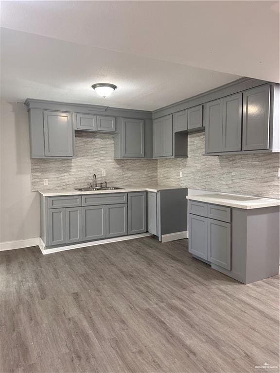 kitchen with backsplash, gray cabinetry, sink, and dark hardwood / wood-style flooring