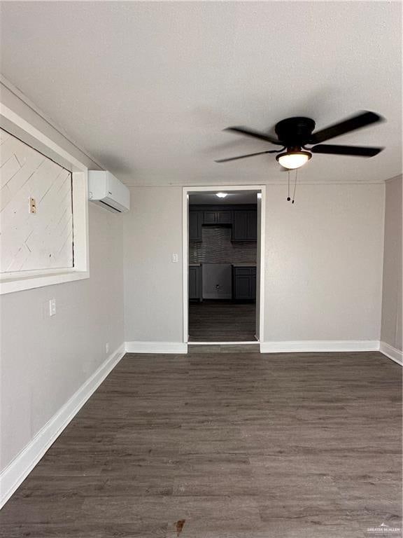 unfurnished room with a textured ceiling, ceiling fan, an AC wall unit, and dark wood-type flooring