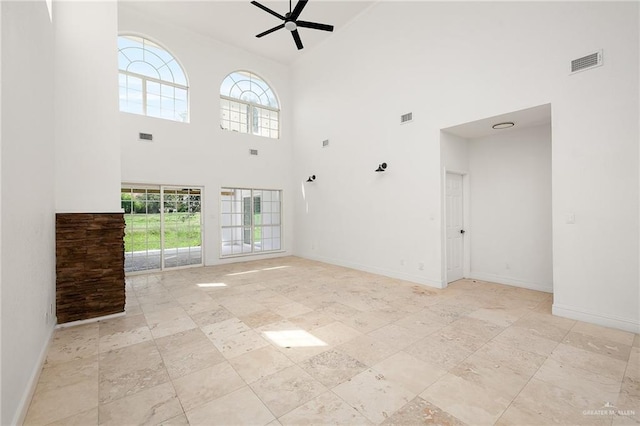 unfurnished living room featuring ceiling fan, a high ceiling, and a wealth of natural light