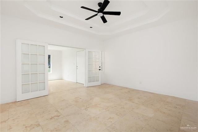 empty room featuring french doors, a raised ceiling, ceiling fan, and built in shelves